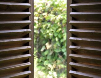 Dark wood plantation shutters open to a view of the garden at a home in Wollongong, NSW