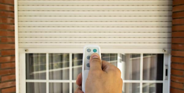 hand pressing a remote control controlling an electric roller shutter in Wollongong , NSW